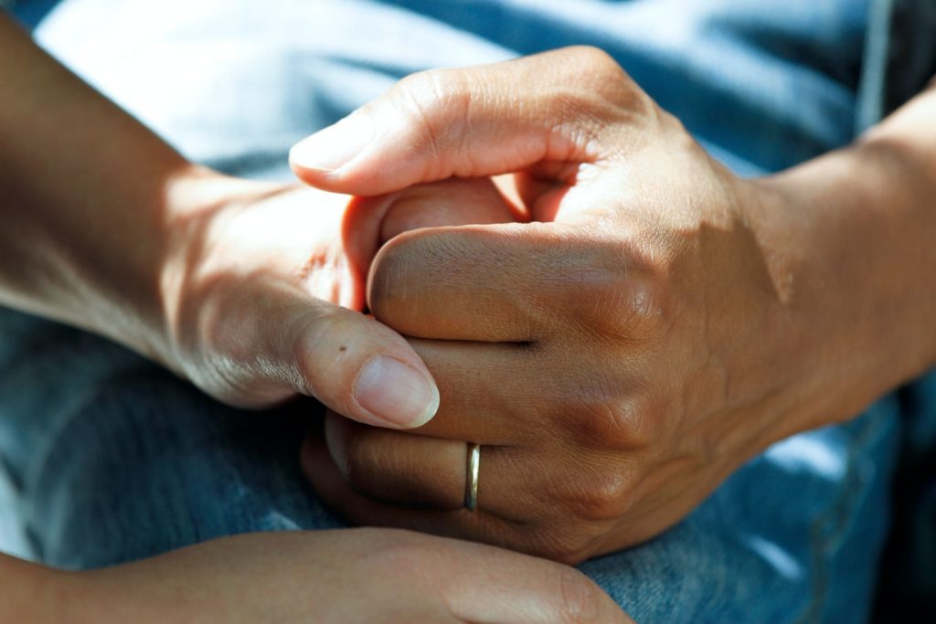 Two people holding hands representing a moment of caring